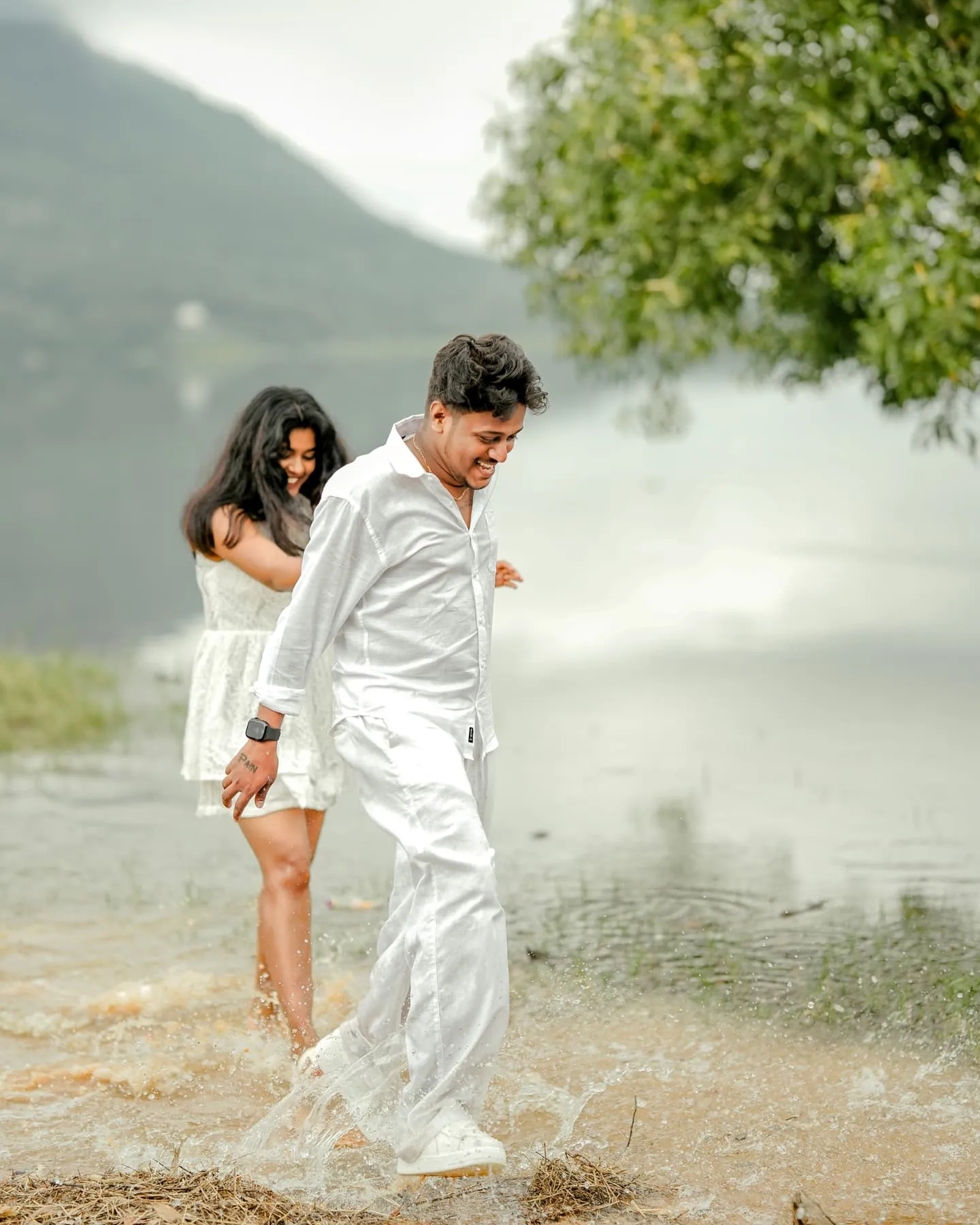 A couple sharing a playful moment beside a mountain lake
